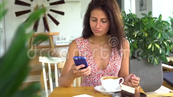 漂亮的年轻女性在咖啡馆做智能手机视频的预览图