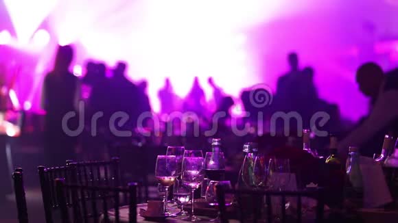 在餐馆或夜总会举行的青年聚会在剪影的背景下摆满酒和食物的宴会桌视频的预览图