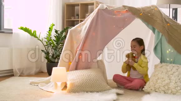 小女孩带着玩具熊在家里的儿童帐篷里视频的预览图