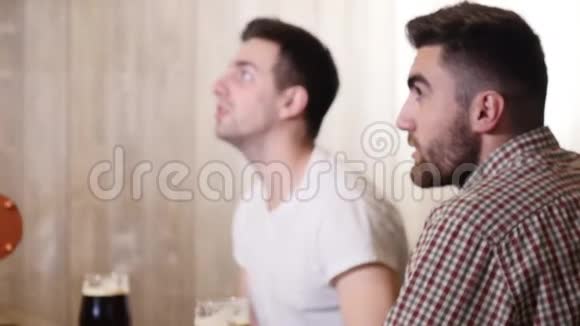 两个年轻人的朋友坐在酒吧里互相交谈一边喝啤酒视频的预览图