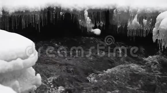 在公园里流着雪的水背景中的冰柱视频的预览图