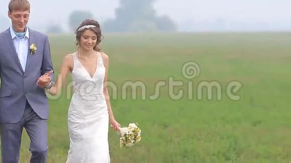 美丽的新婚夫妇正走在绿色的道路上视频的预览图