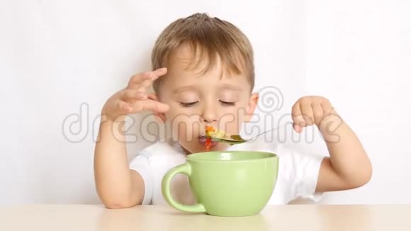 男孩坐在桌旁用勺子吃食物视频的预览图