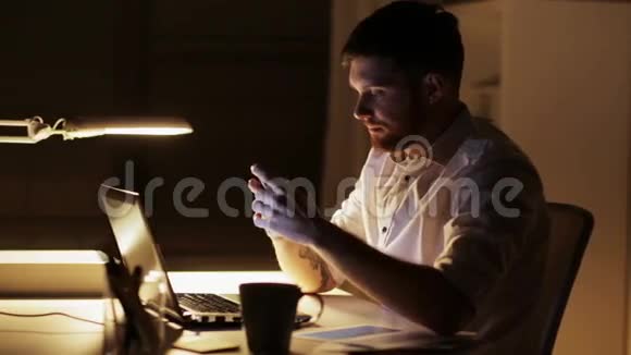 有笔记本电脑和智能手机的人在夜间办公视频的预览图