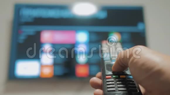 智能电视与应用程序和手男性手握遥控器关闭智能电视男人手生活方式控制电视视频的预览图