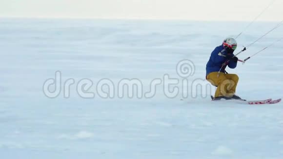 慢动作一名男运动员在滑雪板上表演Kiting他在一个大湖的冰上翻滚滚动他表演各种跳跃视频的预览图