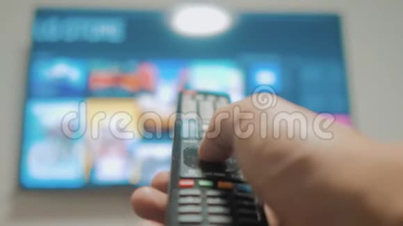 智能电视与应用程序和手男性手握遥控器关闭智能电视手控制电视视频的预览图