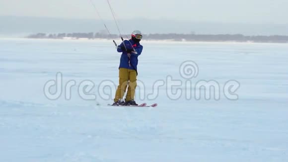 慢动作一名男运动员在滑雪板上表演Kiting他在一个大湖的冰上翻滚滚动他表演各种跳跃视频的预览图