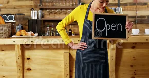 女服务员在咖啡馆里展示有开放标志的石板视频的预览图