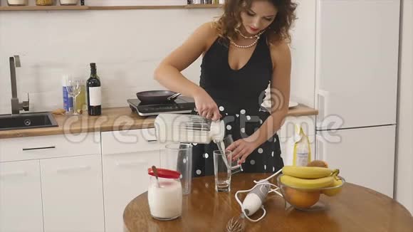 年轻的女人用厨房里的搅拌器在碗里准备面团混合原料自制食物慢镜头视频的预览图