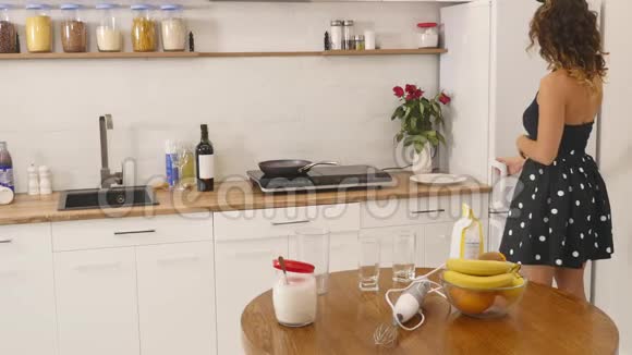 年轻的女人用厨房里的搅拌器在碗里准备面团混合原料自制食物慢镜头视频的预览图