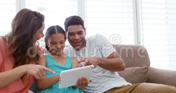 幸福的家庭坐在沙发上使用数字平板电脑视频的预览图