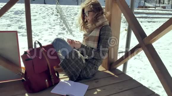 一个年轻的女人坐在木廊上用手指默默地触摸折纸飞机然后把它放在她的身上视频的预览图
