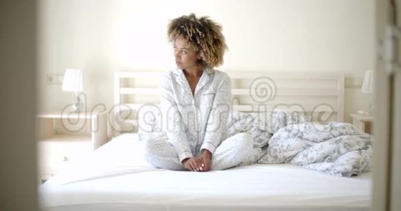 穿睡衣的女人坐在床上视频的预览图