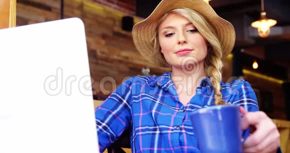漂亮的女人一边喝咖啡一边用手提电脑视频的预览图