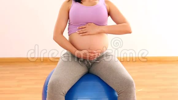 坐在蓝色运动球上的孕妇视频的预览图