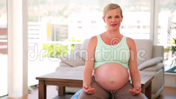 坐在蓝色运动球上的孕妇视频的预览图