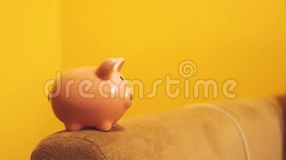 猪银行的经营理念一只手把硬币放在生活方式中一个黄色背景上的储蓄罐省钱就是视频的预览图