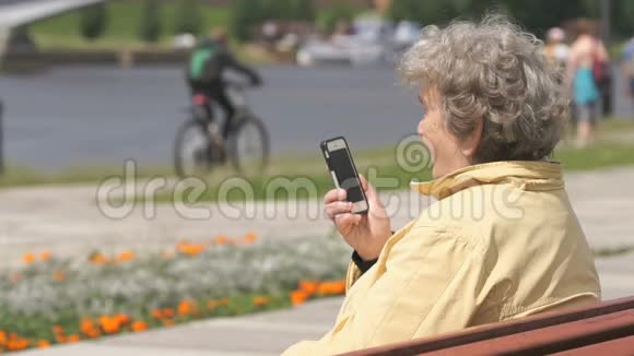 成熟的老妇人在户外用手机说话视频的预览图