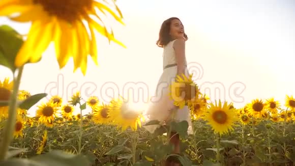 快乐的小女孩在夏天向日葵的阳光下美丽的生活方式日落小女孩向日葵视频的预览图