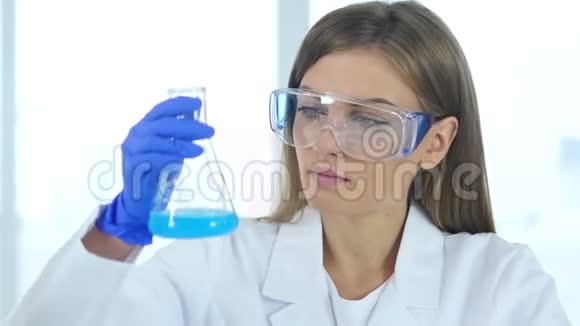 女科学家在实验室里观察瓶中的蓝色溶液视频的预览图