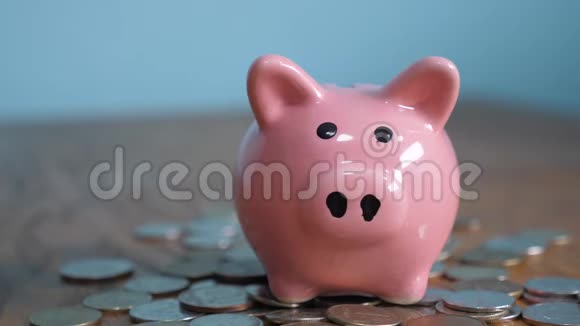 猪银行业务站在一堆硬币的概念上一只手把生活方式硬币放在黄色的储蓄罐里视频的预览图