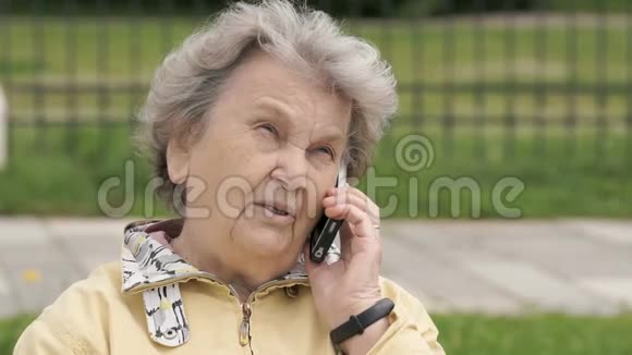 成熟的老妇人在户外用手机说话视频的预览图