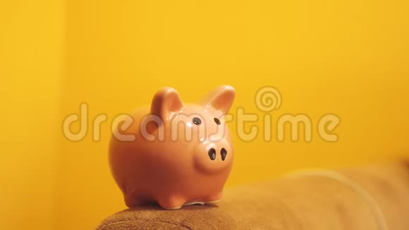 猪银行的经营理念一只手正把一枚硬币放在一个黄色背景的生活方式的储蓄罐里省钱就是视频的预览图