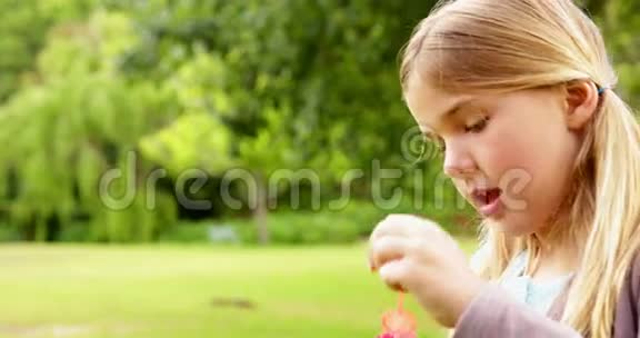 可爱的小女孩在公园里吹泡泡视频的预览图