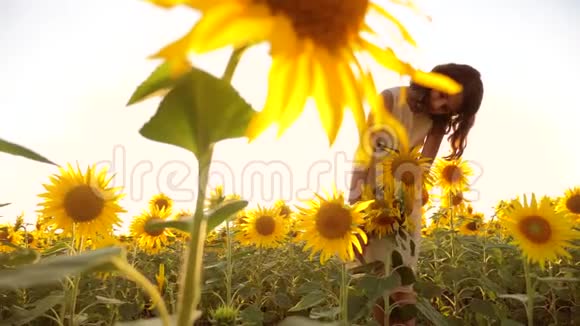 快乐的小女孩在夏天向日葵的阳光下美丽的日落生活方式小女孩向日葵视频的预览图
