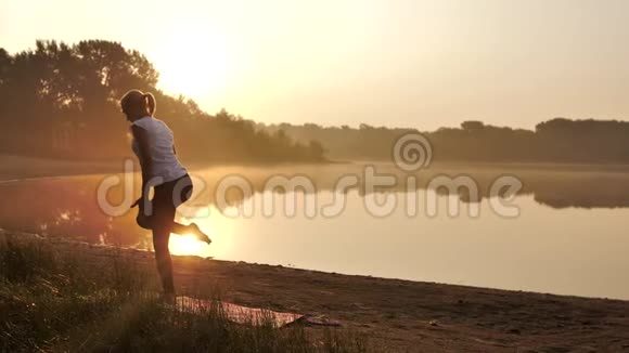 日落时分年轻女子在海滩上练习瑜伽视频的预览图