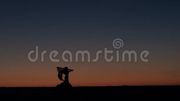 女孩在海滩上和美丽的日落跳舞剪影式视频的预览图