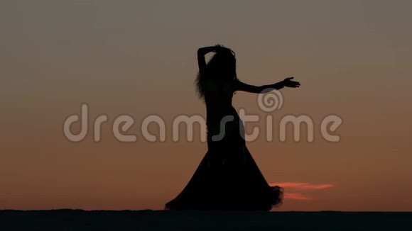 女孩在海滩上和美丽的日落跳舞剪影式视频的预览图