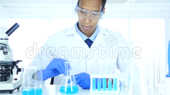 实验室里研究瓶中蓝色溶液的科学家视频的预览图