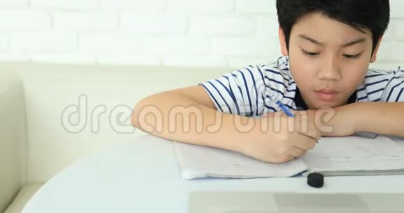 可爱的亚洲男孩在家做家庭作业面带笑容视频的预览图