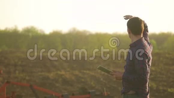 农夫用平板电脑阅读或分析一份报告在一个农业领域阳光下有复古的色调a视频的预览图
