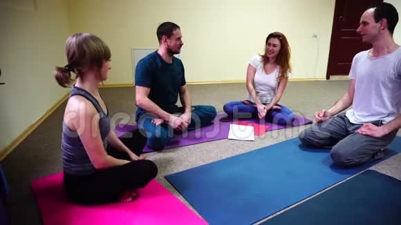 两个年轻的女人和两个男人坐在健身工作室的地板上视频的预览图