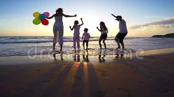 日落时分在海滩上玩耍的快乐人们的剪影视频的预览图