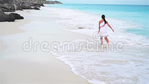 白色热带海滩上年轻美丽的女人在海边散步的女孩慢动作视频的预览图