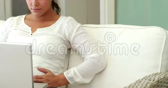 孕妇用笔记本电脑在沙发上放松视频的预览图