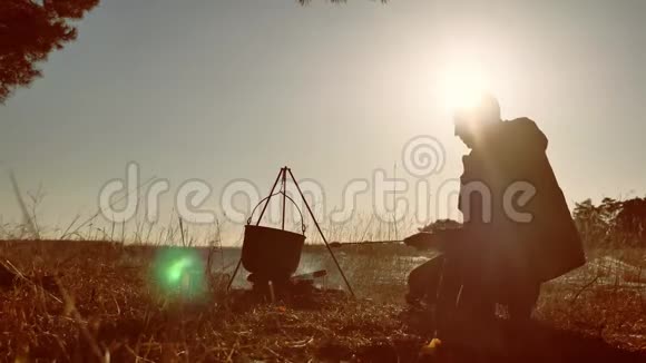 男子旅游啤酒是坐着的生活方式由篝火晚会在大自然露营剪影阳光日落男子剪影视频的预览图