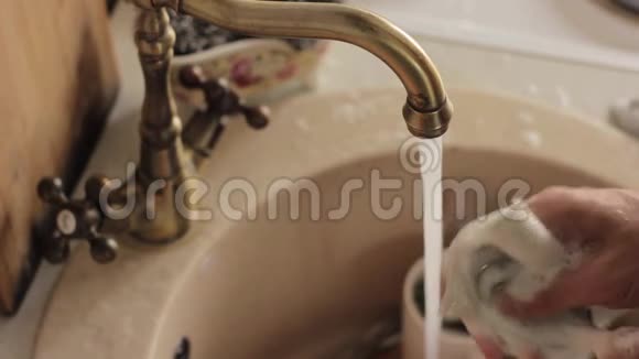 男人洗盘子冲洗泡沫和洗涤剂的盘子视频的预览图
