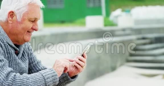 在海滩上使用手机的老人视频的预览图
