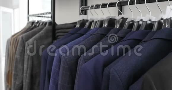 一排男人在衣架上穿夹克商店里挂在衣架上的新漂亮衣服视频的预览图