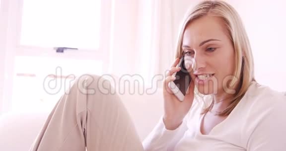 金发女人坐在沙发上打电话视频的预览图