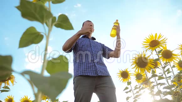 农夫手里拿着一个塑料瓶向日葵油站在田野里慢动作视频葵花籽油视频的预览图
