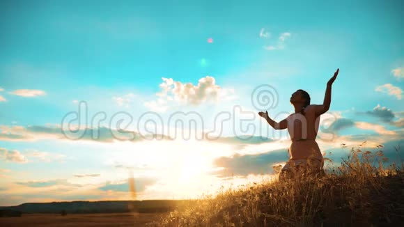 女孩在日落时双手交叉祈祷剪影女人跪着祈祷慢动作视频生活方式女孩视频的预览图