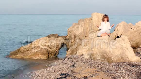 坐在海边岩石上的小女孩视频的预览图