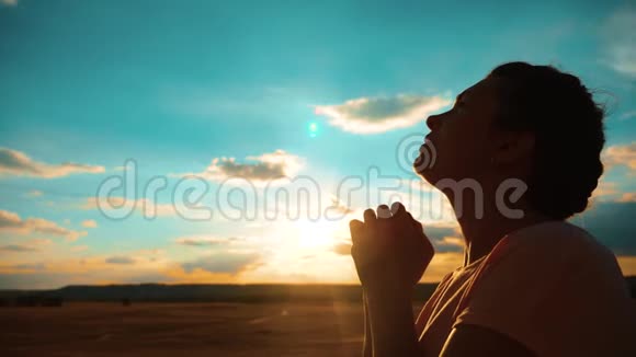 女孩在祈祷日落时分女孩双手合十形成祈祷的剪影慢动作视频女孩双手合十祈祷视频的预览图