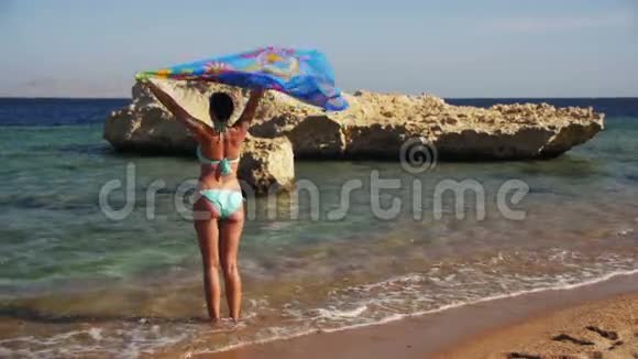 带着围巾在夏季海滩慢动作散步的快乐女人视频的预览图
